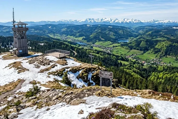 KI-generiertes Symbolbild: Gipfelplateau mit Restschnee, Aussichtsturm und Alpen am Horizont